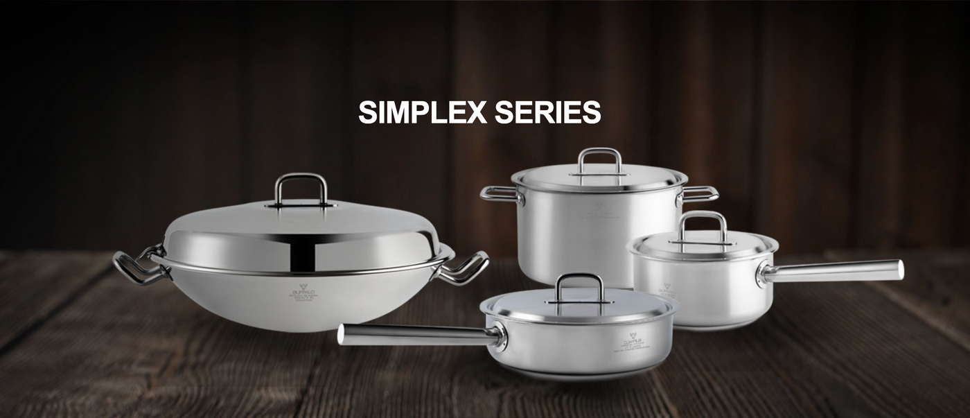 A set of four shiny stainless steel pots and pans from Simplex Series on a wooden table.