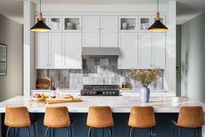 Modern kitchen interior with hanging lights, bar stools, and gas stove, installed with an app-enabled SC98 Pacific range hood.